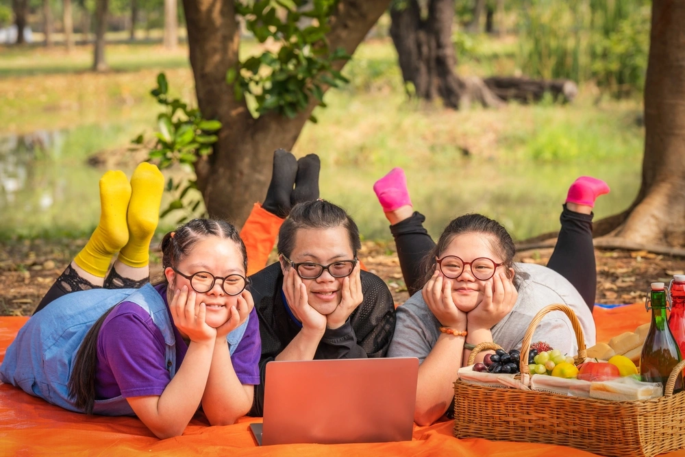 Three woman with down syndrome watching a movie together in a park