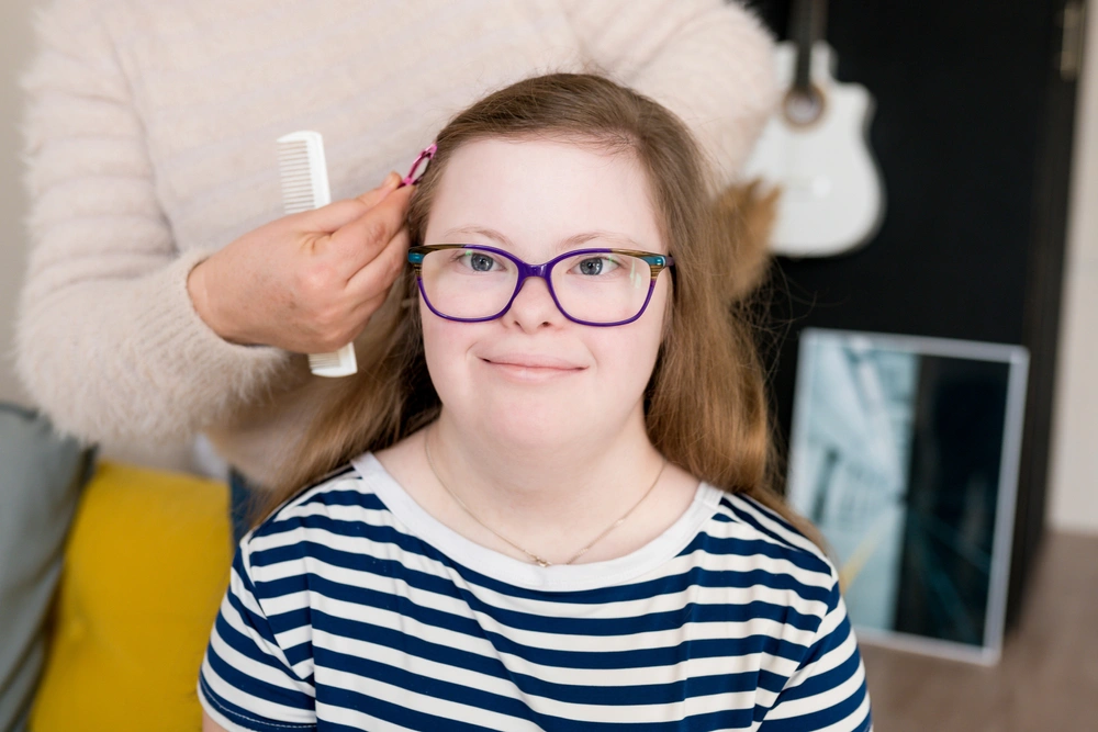 carer helping a disabled girl with downsyndrome comb her hair