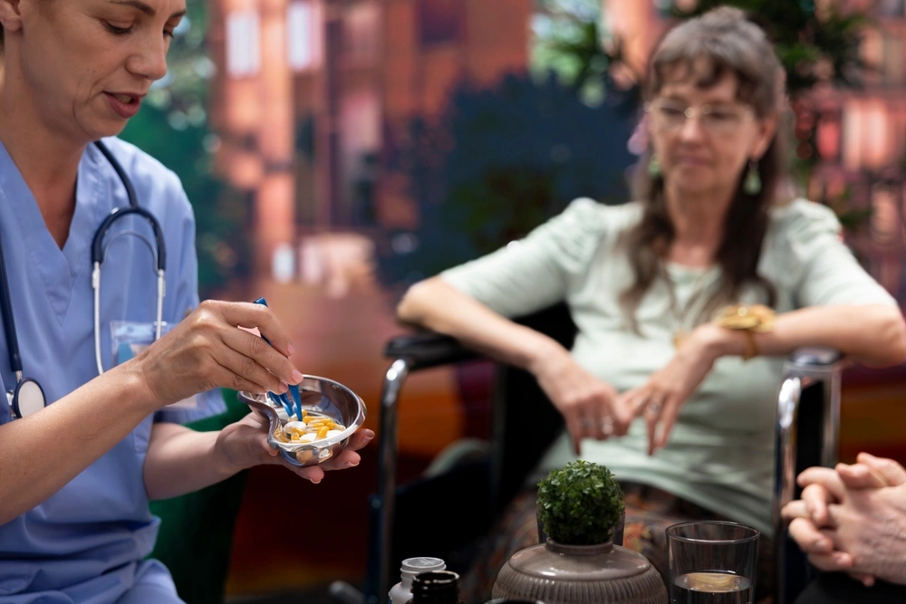 nurse feeding medicine to a elderly age woman on wheel chair