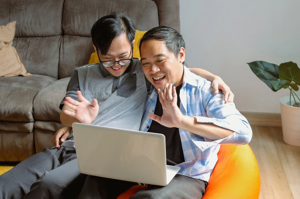 A man helping a disabled guy and looking at laptop